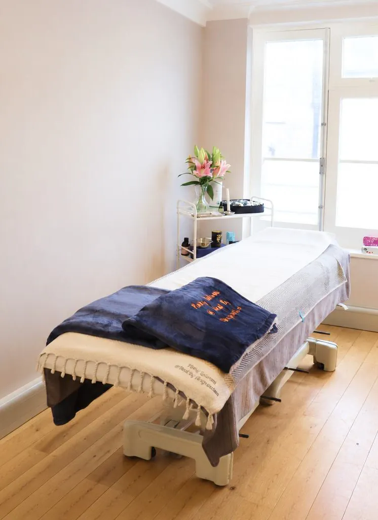 Bright acupuncture treatment room with a prepared treatment couch